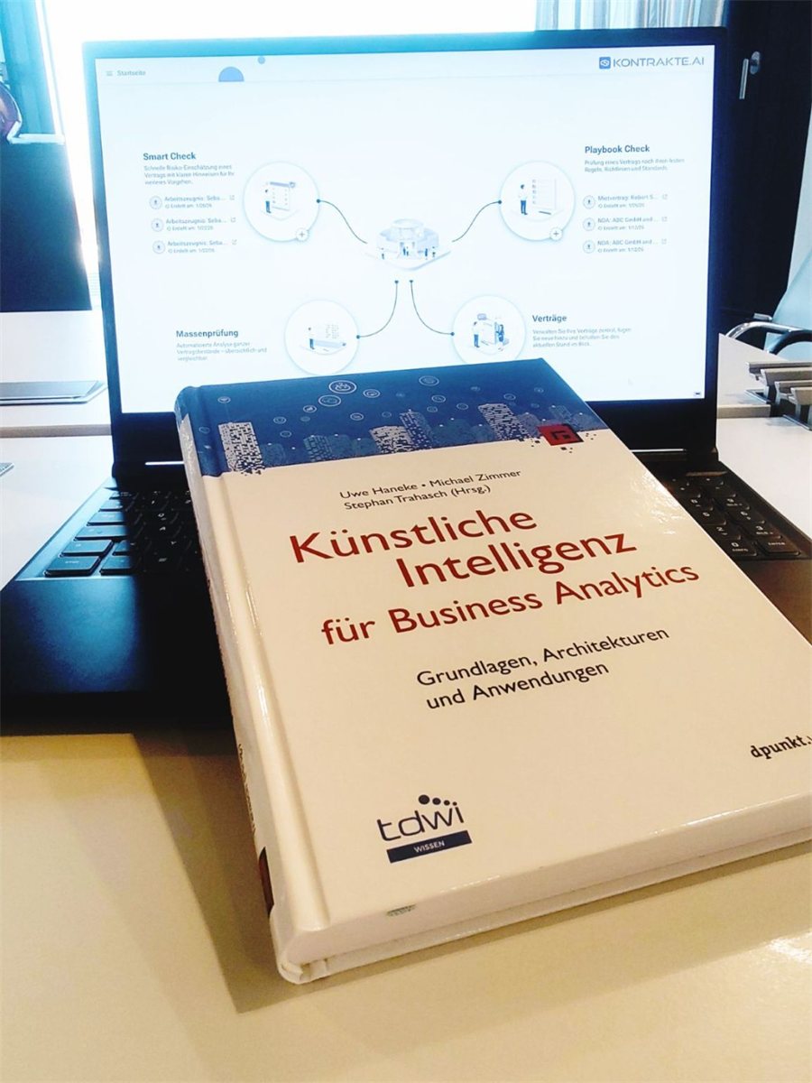 The edited volume “Künstliche Intelligenz für Business Analytics” (dpunkt.verlag) in front of a laptop showing the Kontrakte.AI start page